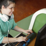 Visually impaired woman with headphones using a braille terminal