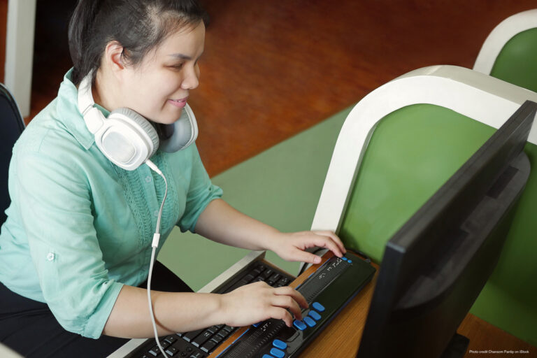 Visually impaired woman with headphones using a braille terminal